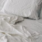 수면의 질을 높이는 한국인의 새로운 습관, 실천법은? A rumpled white duvet and pillows on a bed.