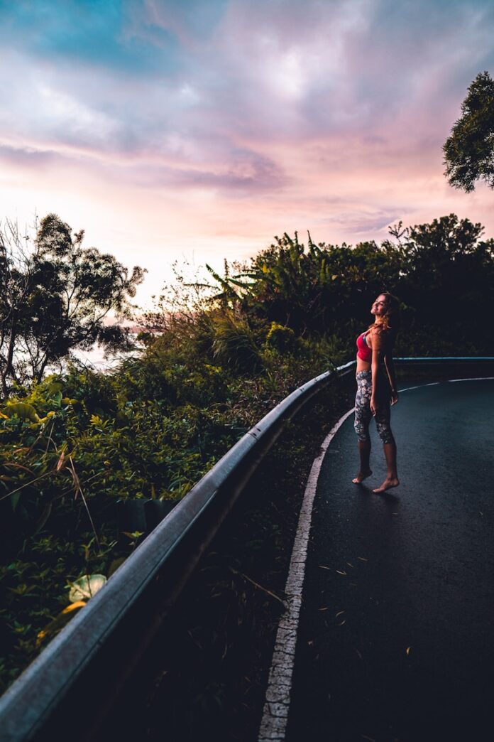Photo by Matthew Sichkaruk woman in red tank top and blue denim jeans walking on gray concrete road during daytime