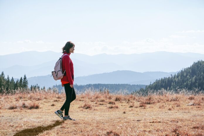 Photo by Levi Kyiv a man with a backpack walking across a dry grass covered field